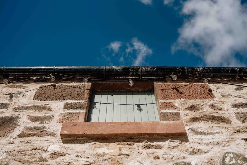 A high level barn door is photographed underneath the bright blue sky. The door is in the courtyard at Kinclune House.