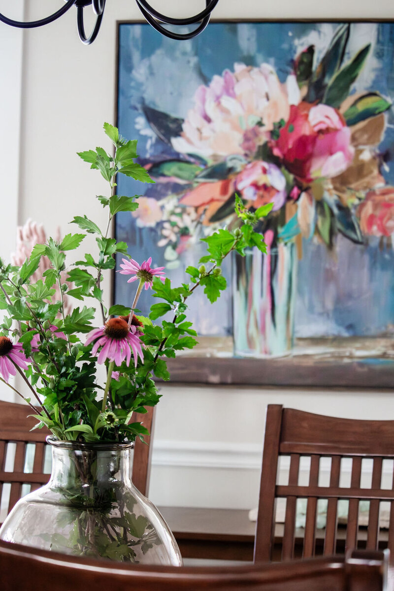 Vase of wildflowers, wooden chairs and colorful floral artwork