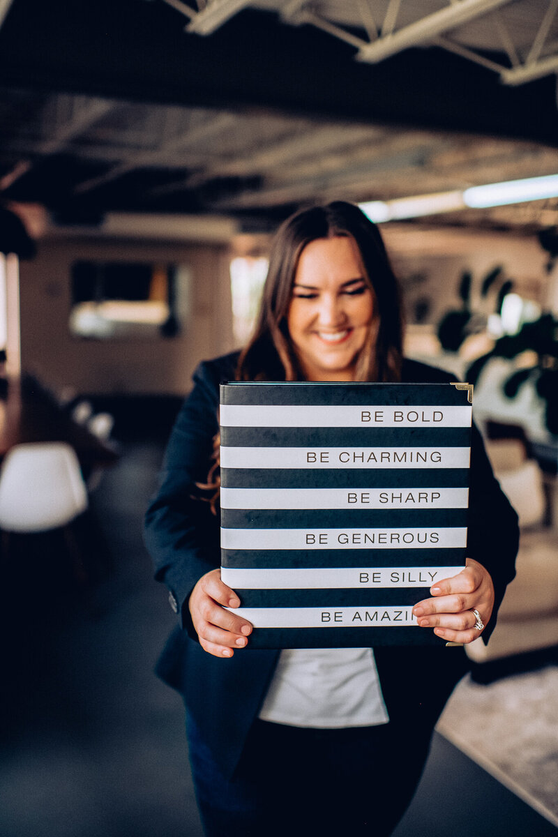 Alaina Biddulph Owner holding inspirational Folder