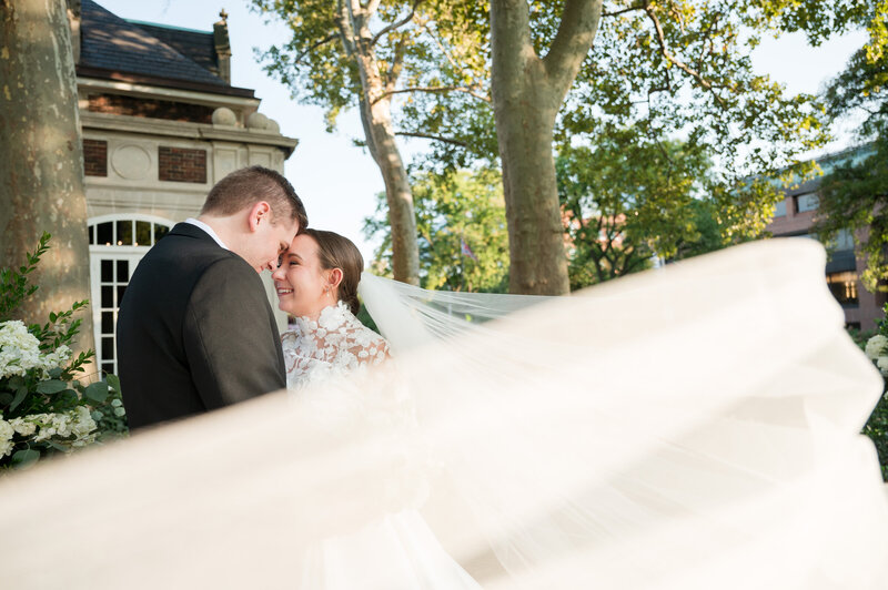 Bride and groom embracing under the bride's veil at the Barn at Wolf Creek