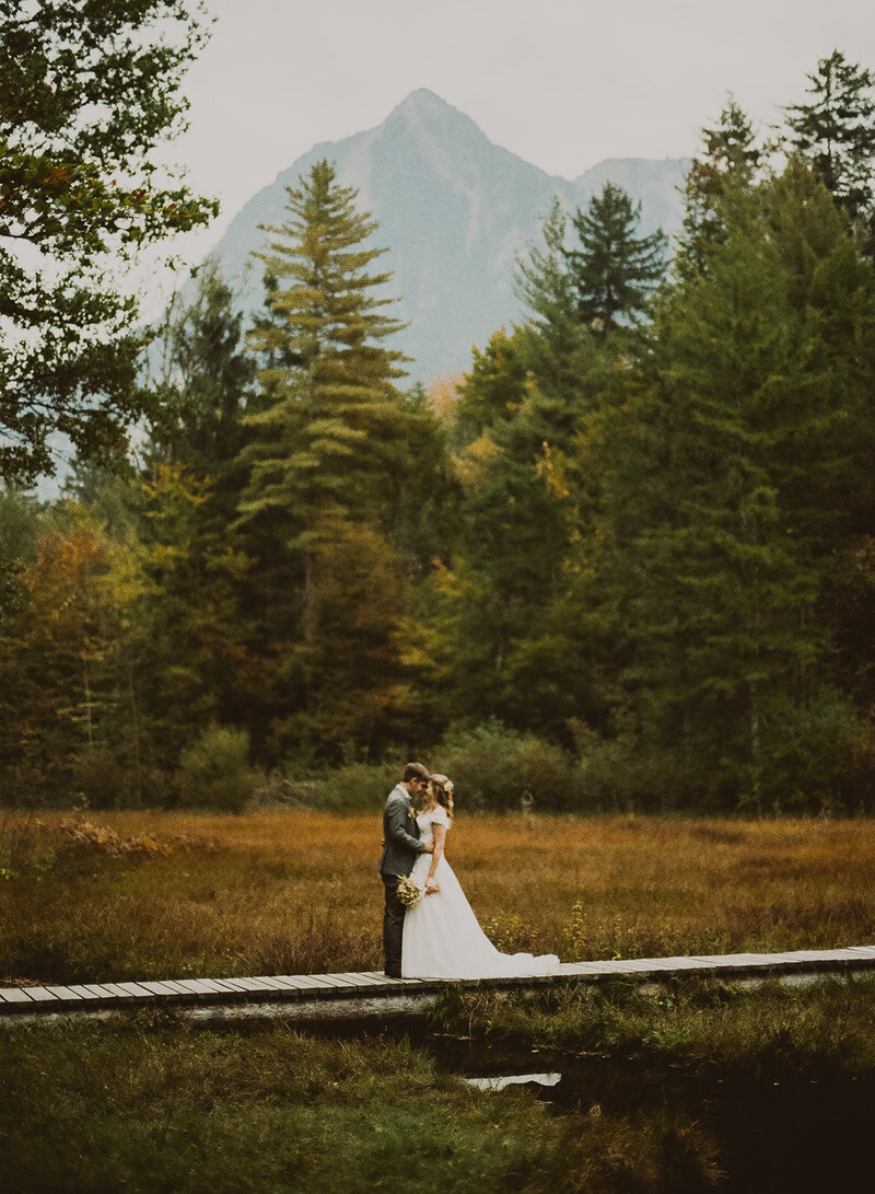Ein analoges Hochzeitsfoto in der Innerschweiz. Hochzeitspaar steht auf einem Steg und im Hintergrund sieht man einen Berg.