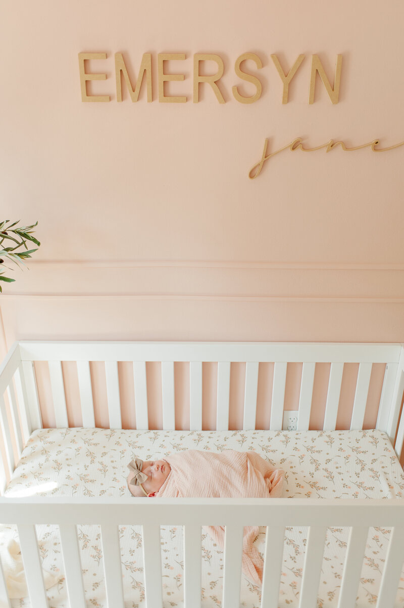 Sweet babygirl laying in her crib asleep while newborn photographer captures the moment