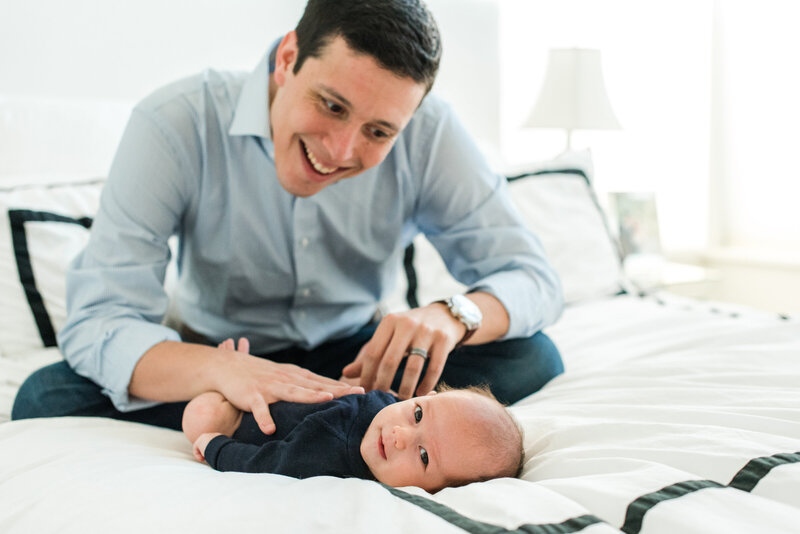 Man smiling at baby lying on a bed