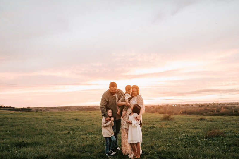 family waking in field at sunset