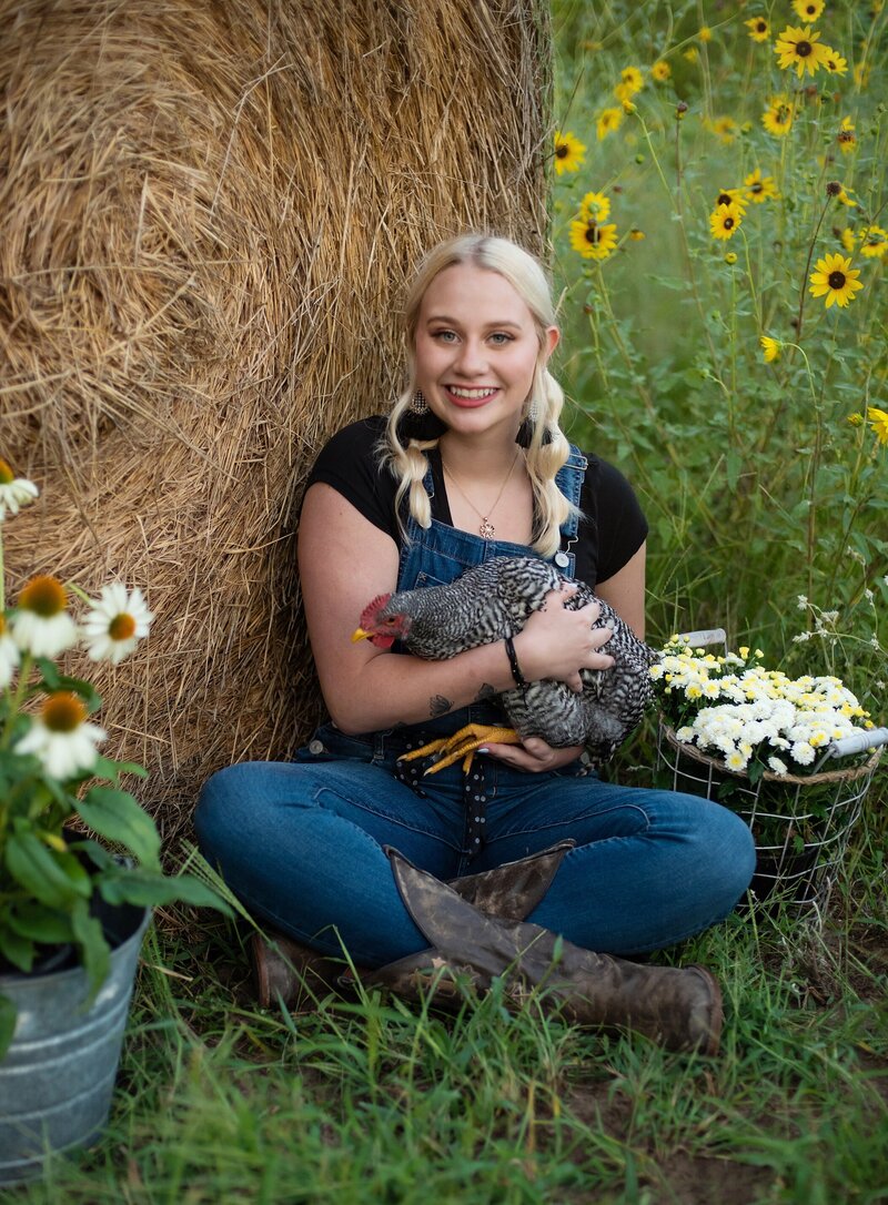 high school senior pictures farm themed shoot girls dreessed in ovralls posing with red tractor