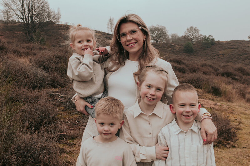 Een vrouw en haar kinderen staan samen in een veld, genietend van de buitenlucht en de natuurlijke omgeving.
