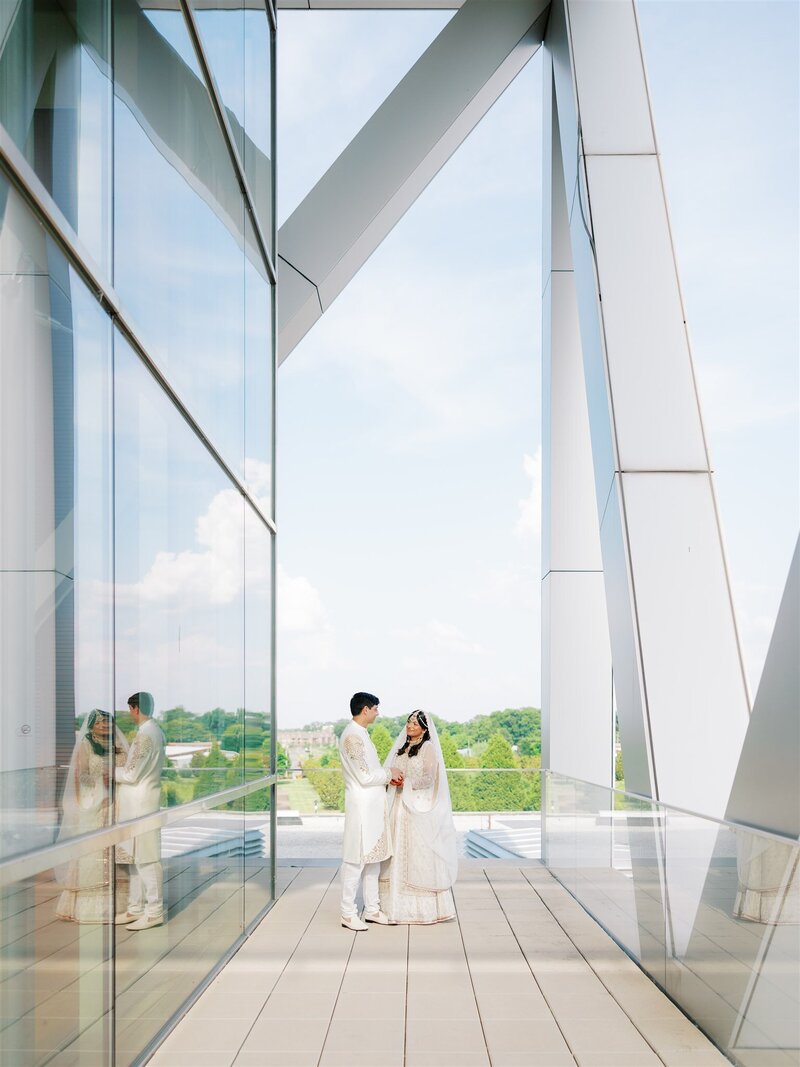 bride and groom stand together on balcony at clinton library in little rock, arkansas