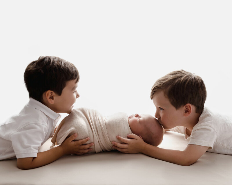 Brothers holding their newborn brother for their family session in Murrysville.