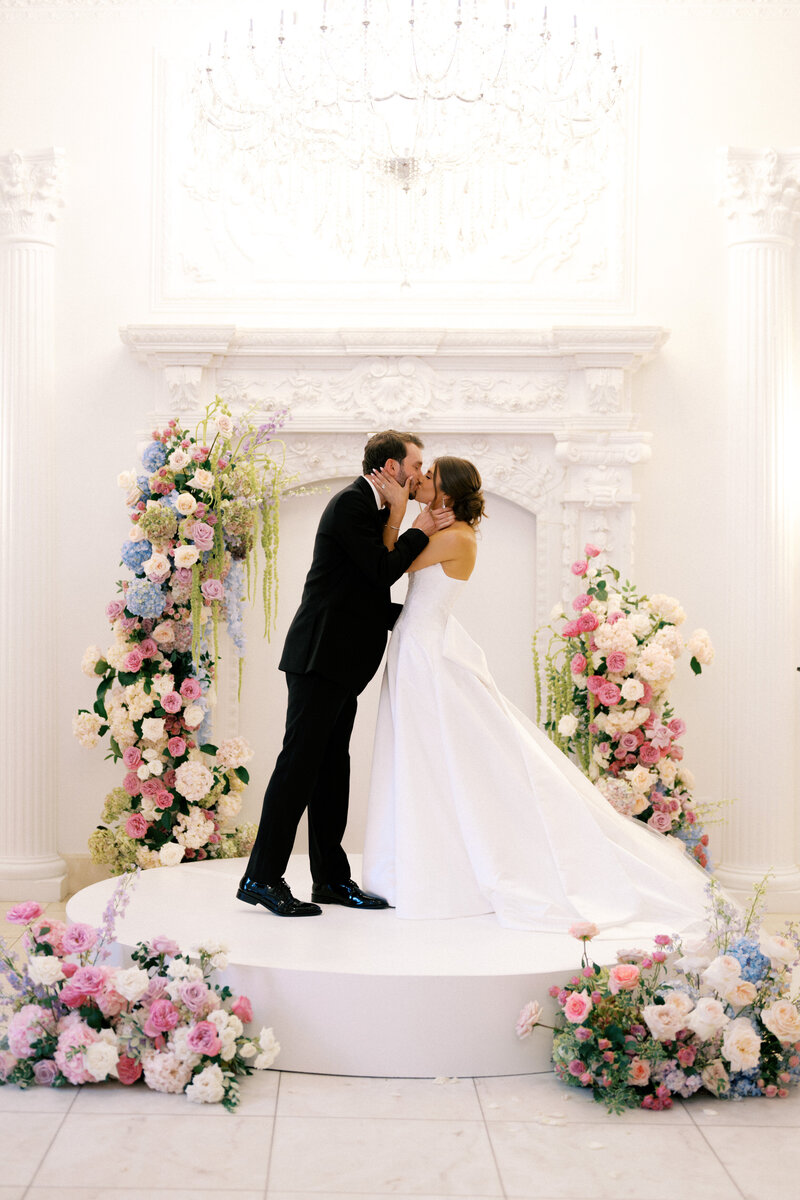 Bride and groom standing in front of a lush floral arch