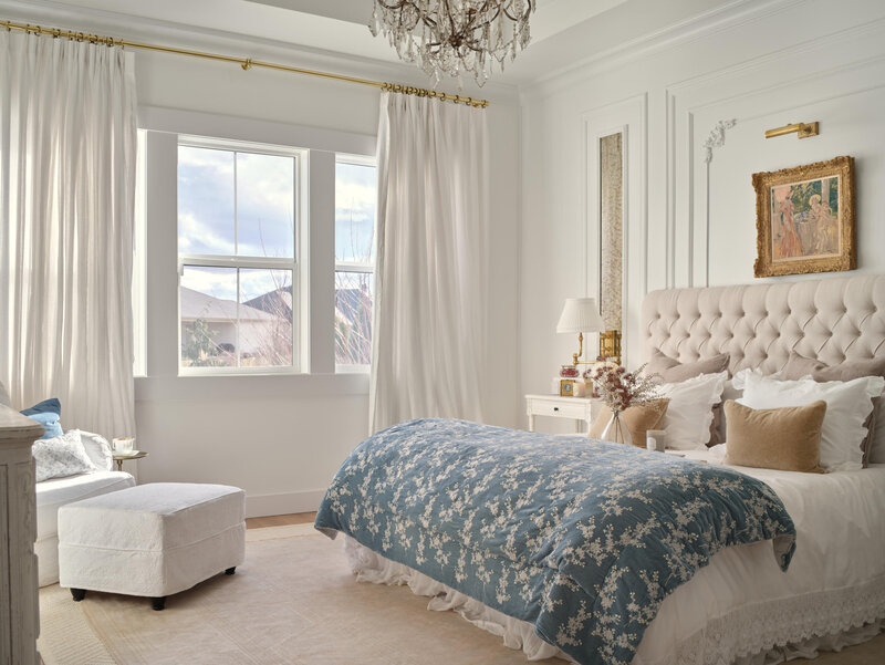 luxury bedroom with white dresser white sitting chiar and bed with blue blanket