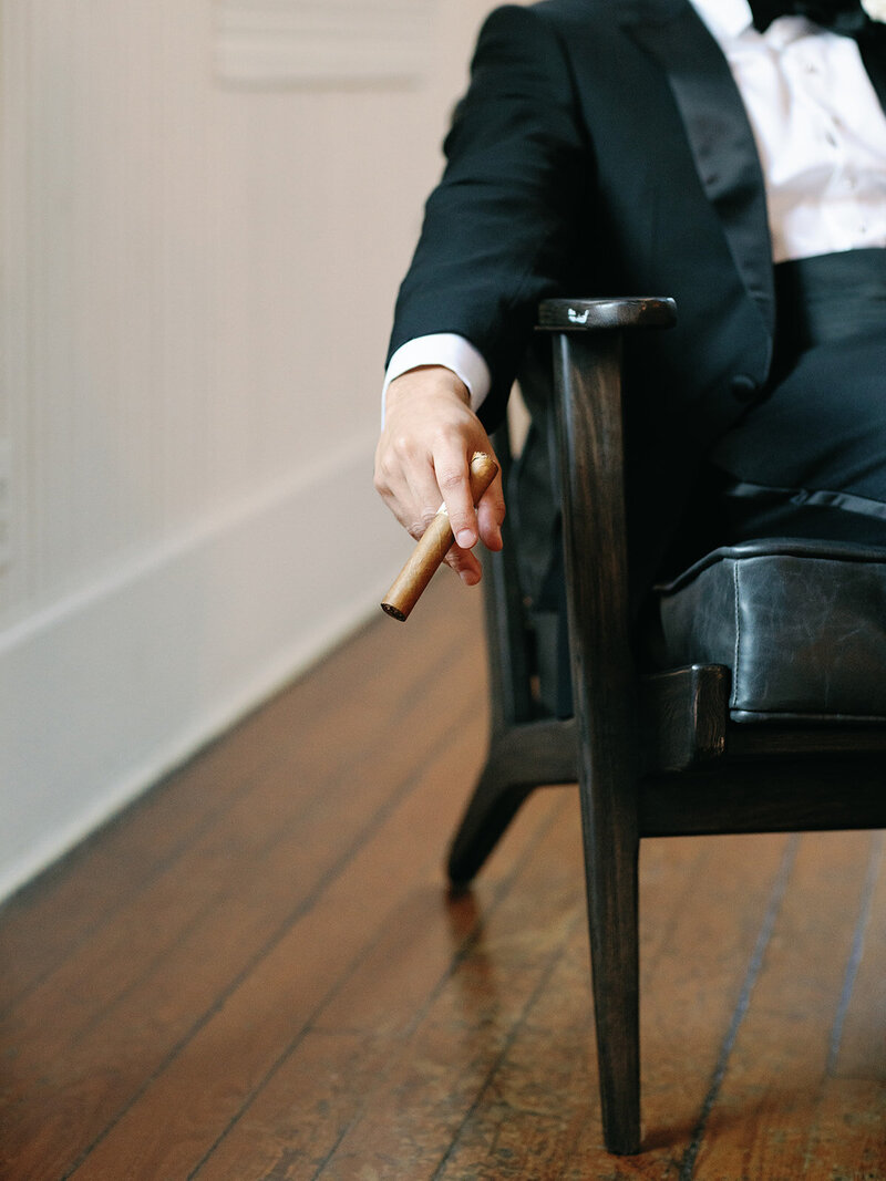 Groom smoking a cigar in a black tux