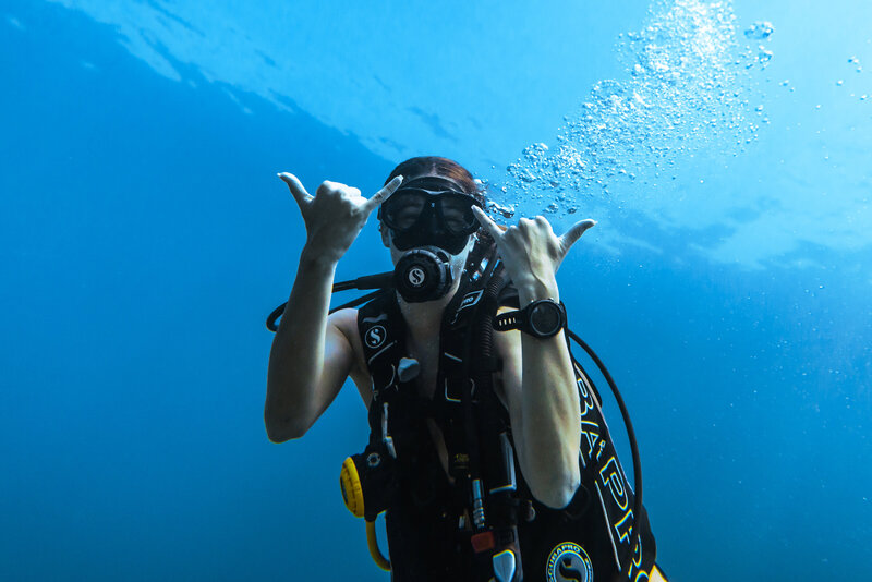 Happy scuba diver underwater blowing bubbles and giving the hang tight symbol