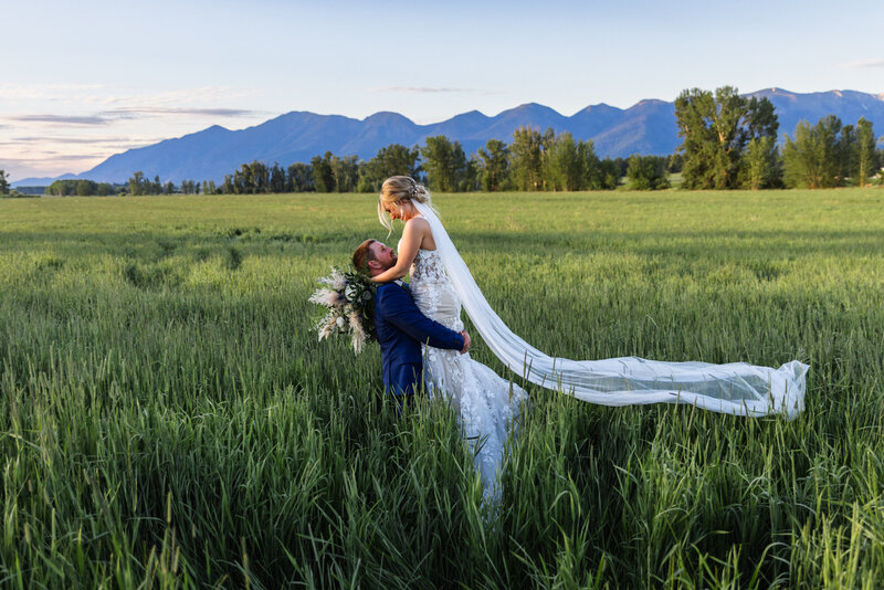 bride and groom kissing by river