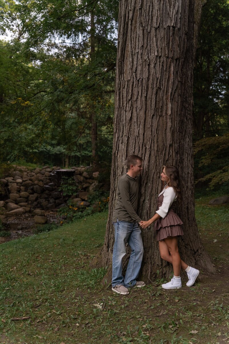 Couple holding hands beside a giant tree at Coxhall Gardens in Carmel, Indiana