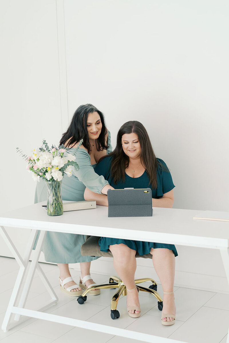 Two wedding planners from Raleigh at desk with laptop