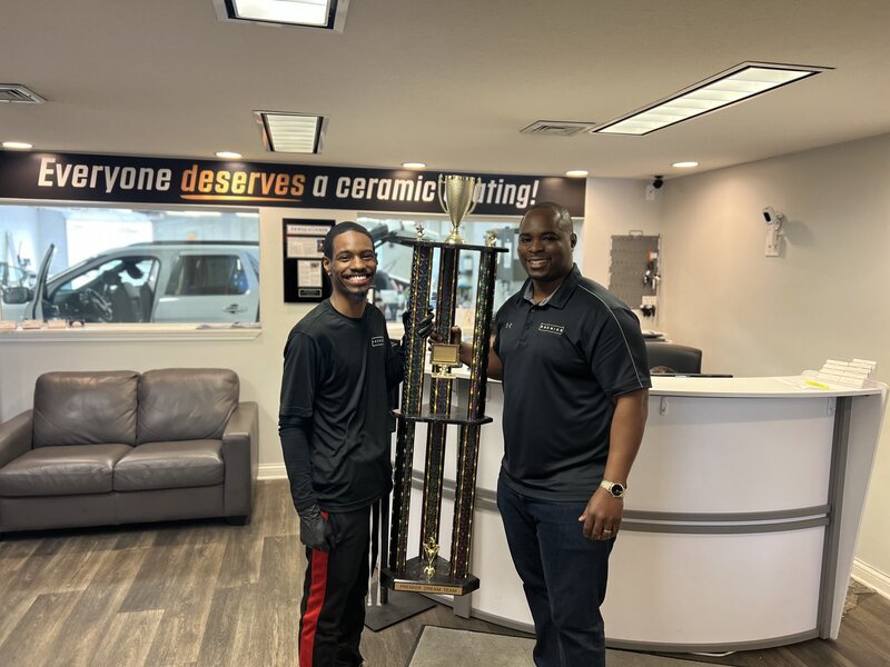 Donte Wilburn and employee smiling and holding trophy