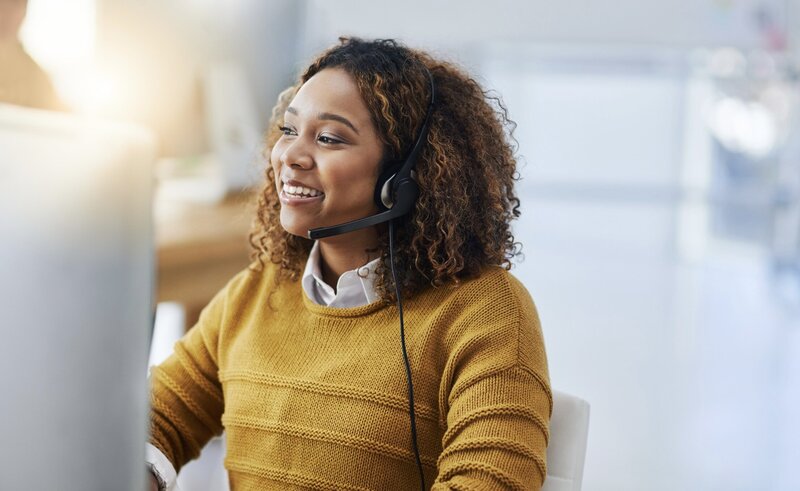 A smiling woman wearing a headset, representing the supportive and customer-focused service provided by Occam Health Services.