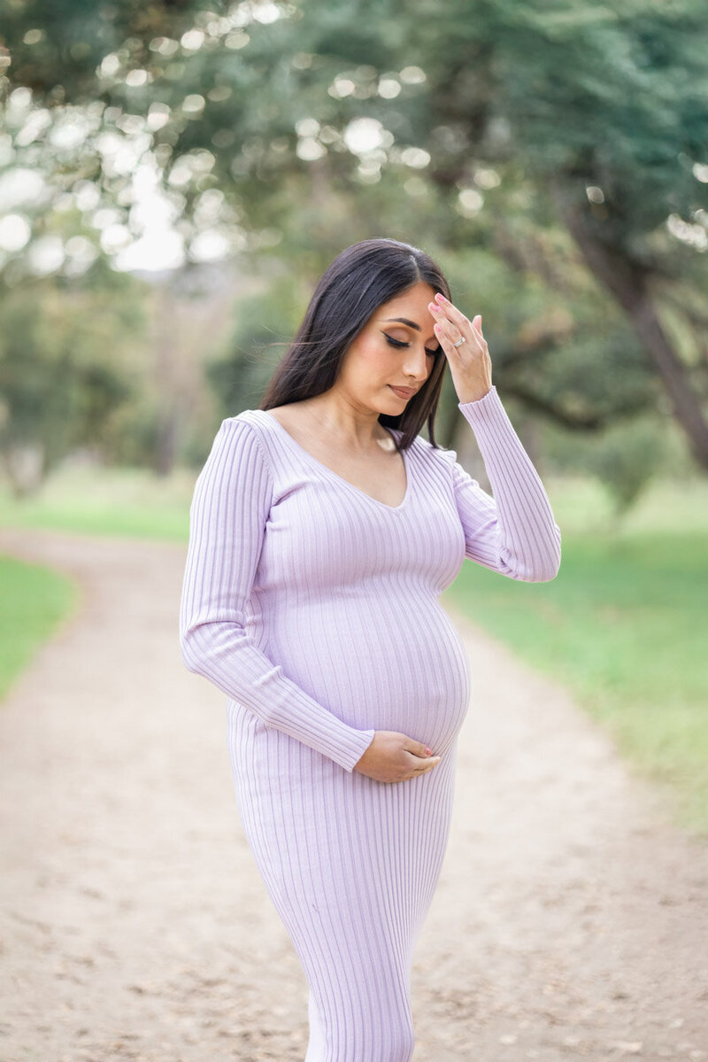 Pregnant mama poses cradling her baby belly during a maternity session at San Jose surrounded by greenery and nature
