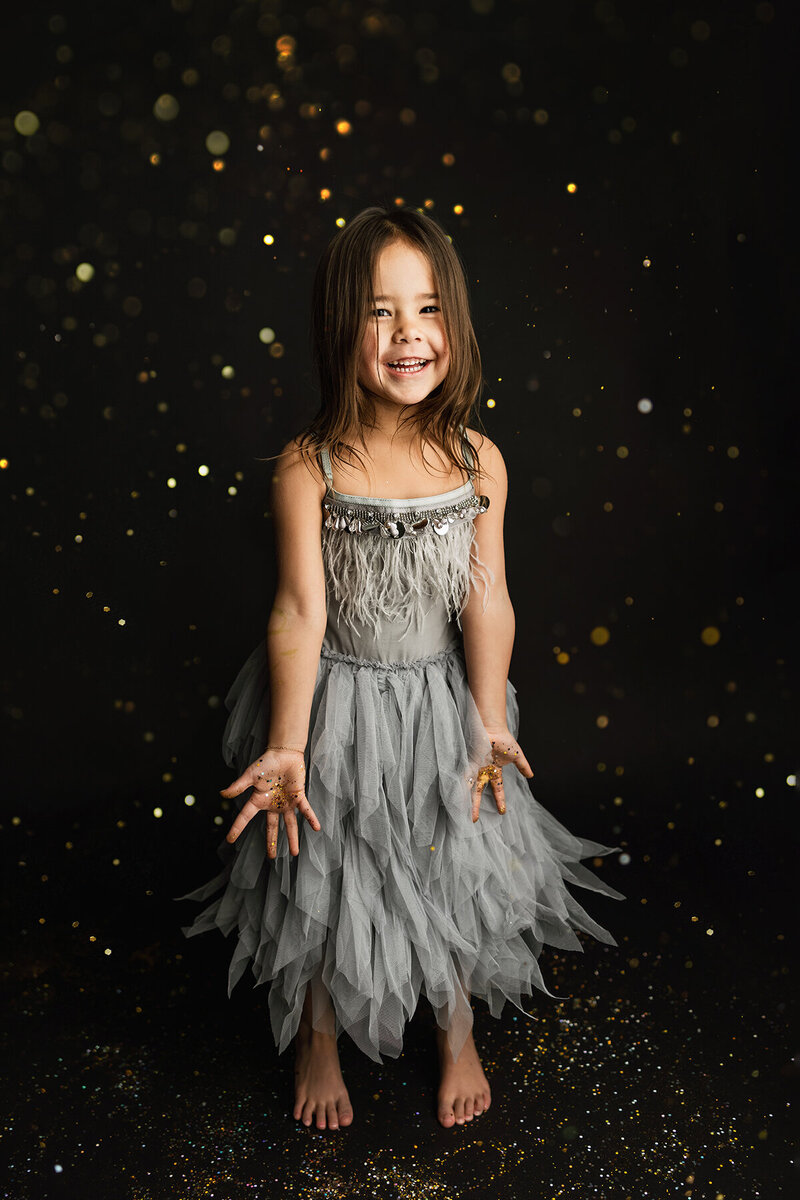 Little girl in Fort Collins wearing a sparkly gray dress throwing glitter