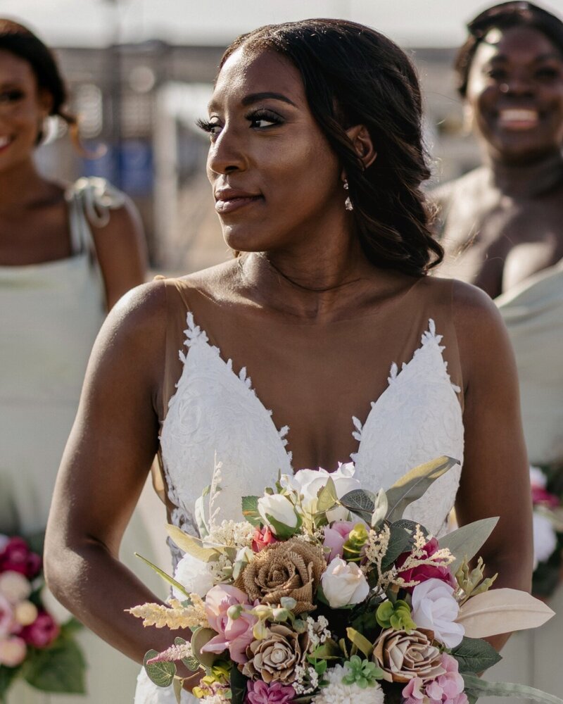 Bride holding a vibrant wedding bouquet with soft glam makeup and a radiant complexion, captured just before the ceremony—makeup by Artistry by Jessica.