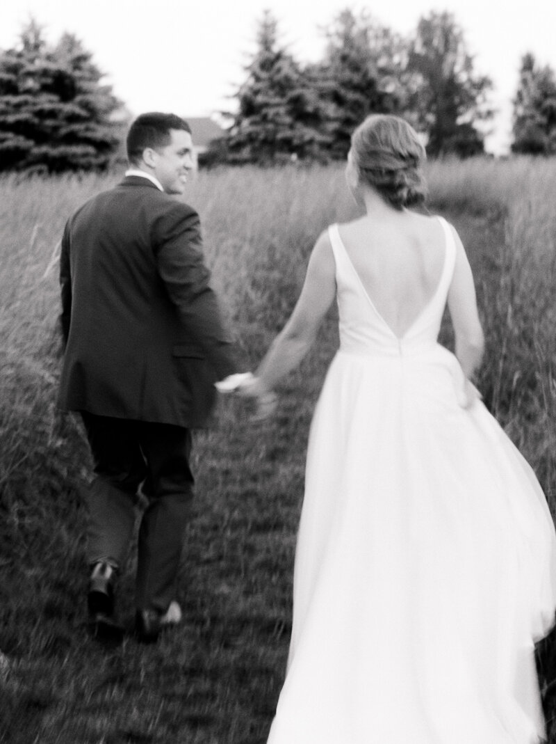 Blurry black and white photo of bride and groom holding hands