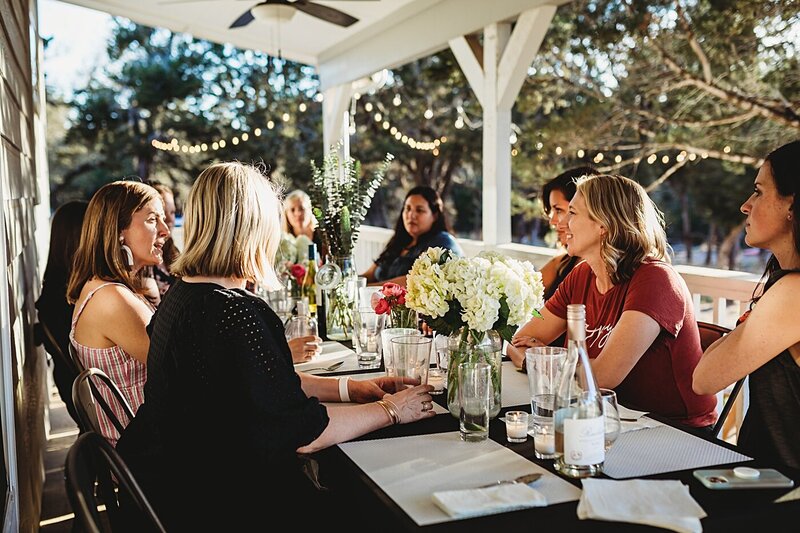 group of female photographers sit around an outdoor dinner table at an in person retreat