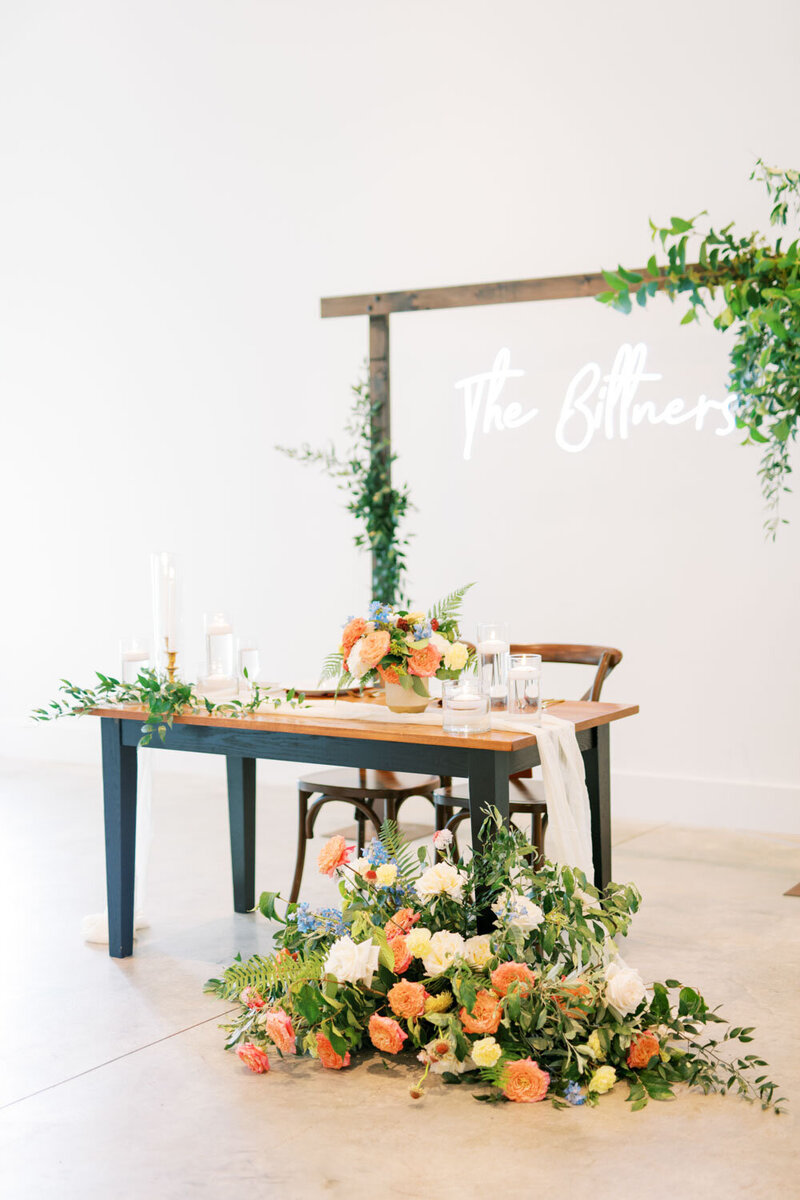 Sweetheart table with floral arrangements and custom sign
