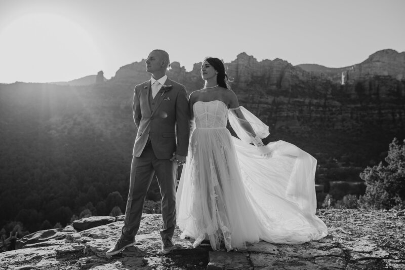 wedding dress with full skirt off the shoulder long sleeves boho bride and groom with sedona red rocks in the back ground
