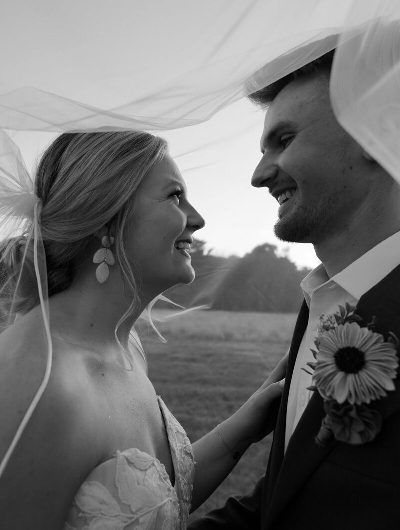 the bride and groom are looking at each other and smiling, black and white photo