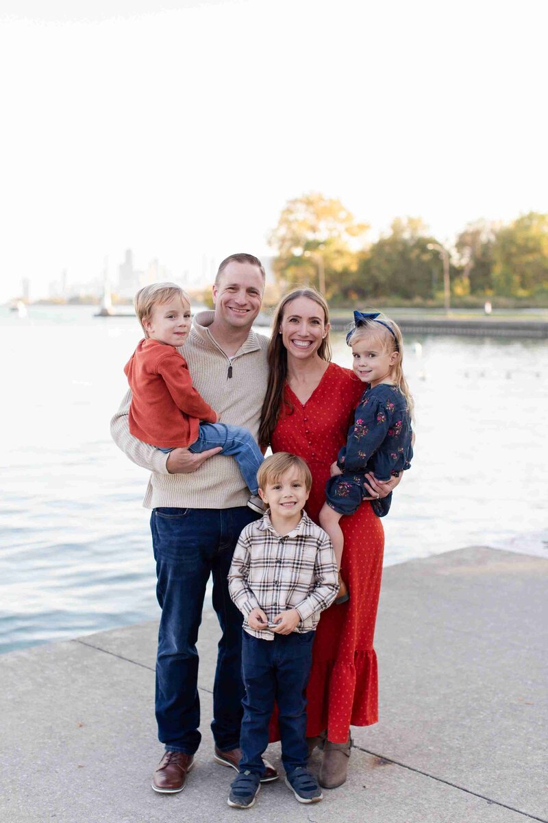 A family smiles together for a photo by the lake, showcasing their joyful moment in a natural setting.