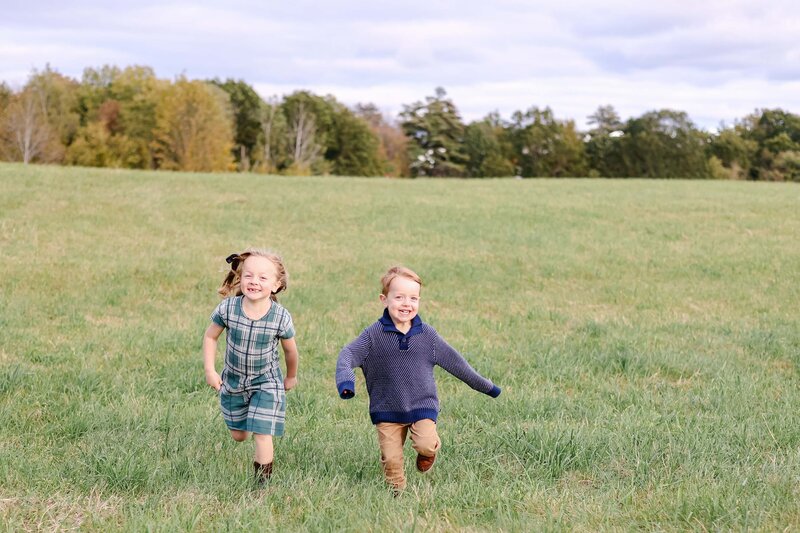 Two toddler siblings running in an open field with NH Family Photographer