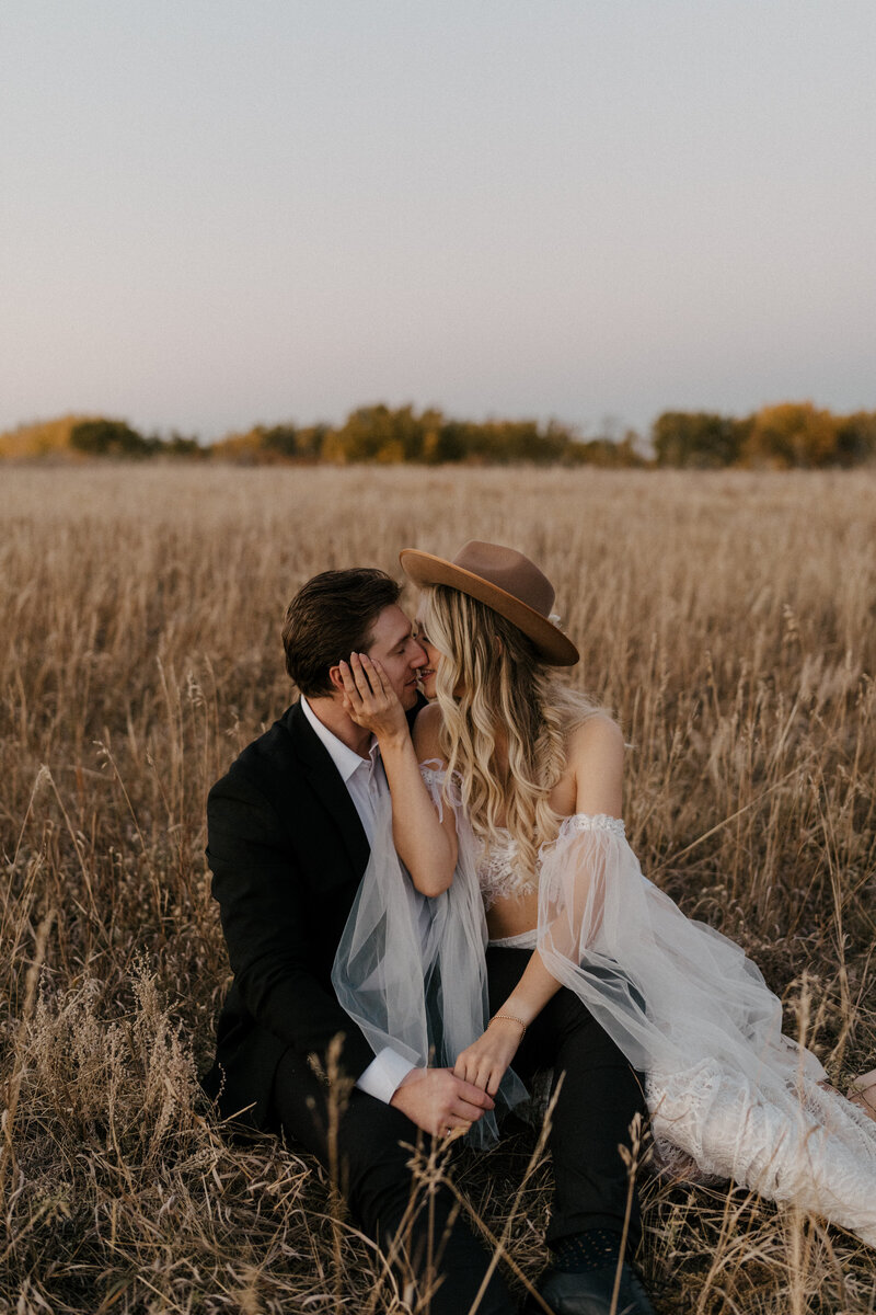 bride and groom kissing behind bride's hat