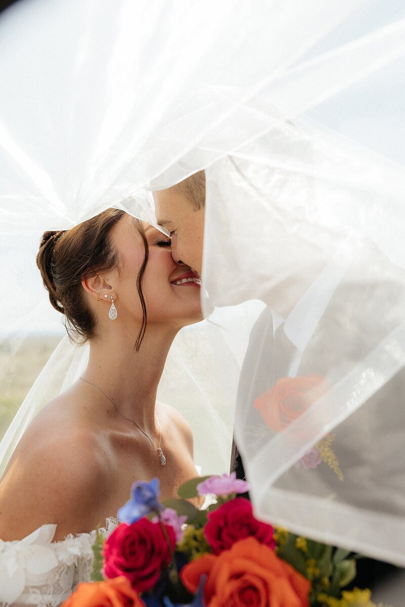 Rylie and Tayhgan kissing under the veil at Silver Spur Ranch in Belle Fourche, South Dakota.