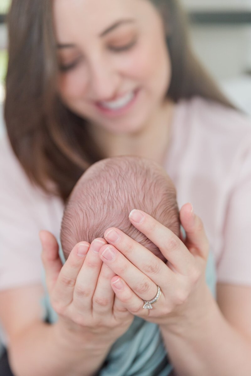 Mom holding newborn's head in palm of hands