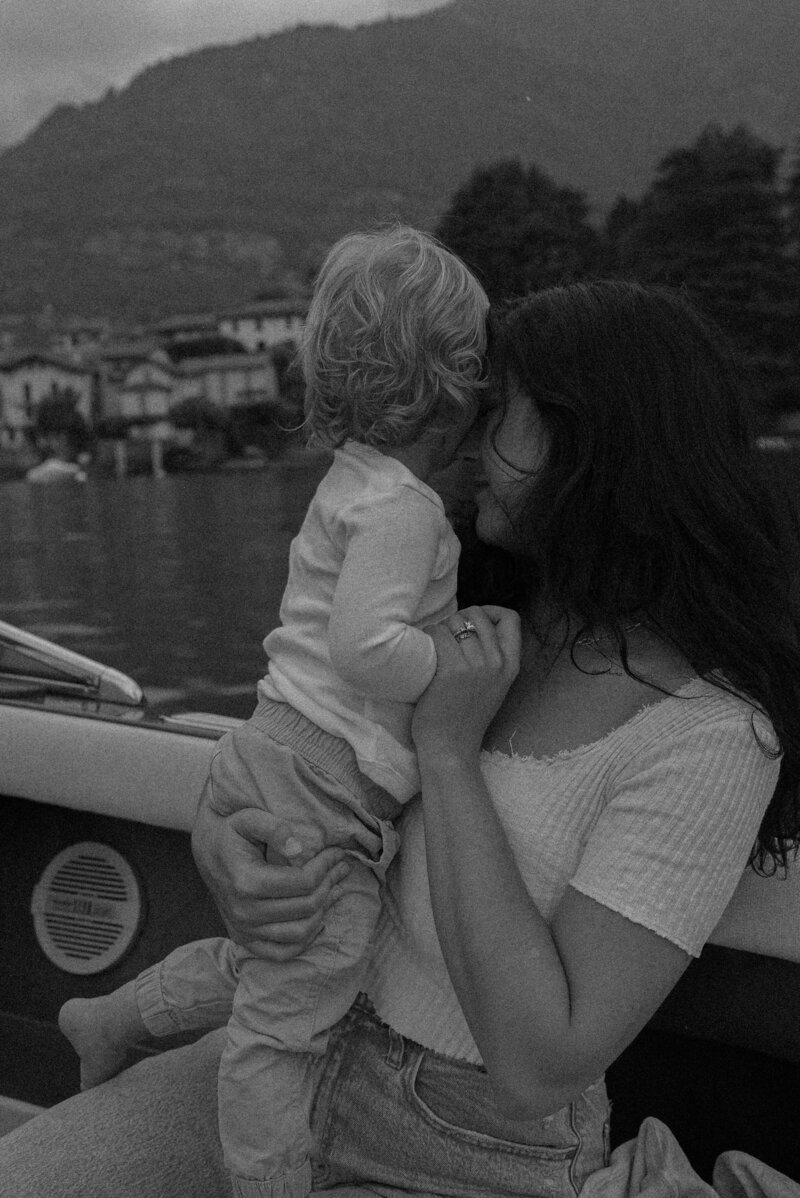Tia Lorae sitting on a boat in lake como holding her baby