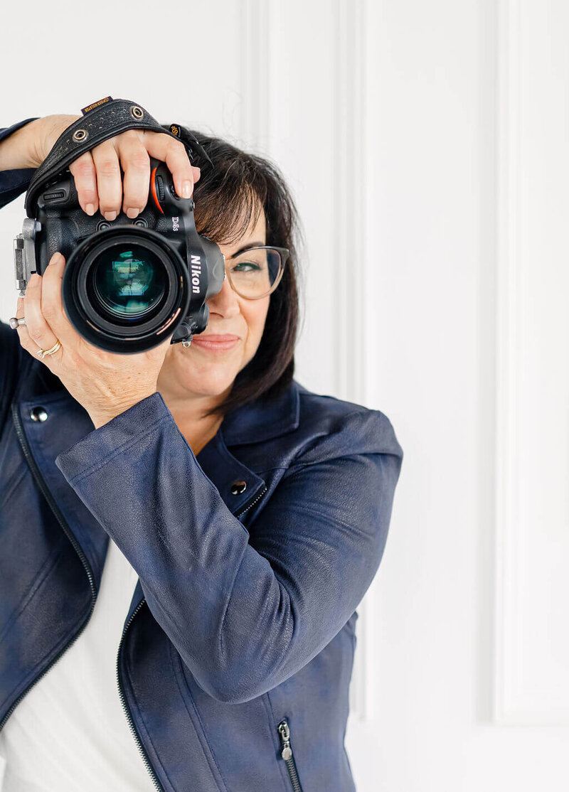 a photo of Ottawa Headshot Photographer Elenora Luberto JEMMAN Photography COMMERCIAL. She's wearing black, sitting on a chair and holding her camera