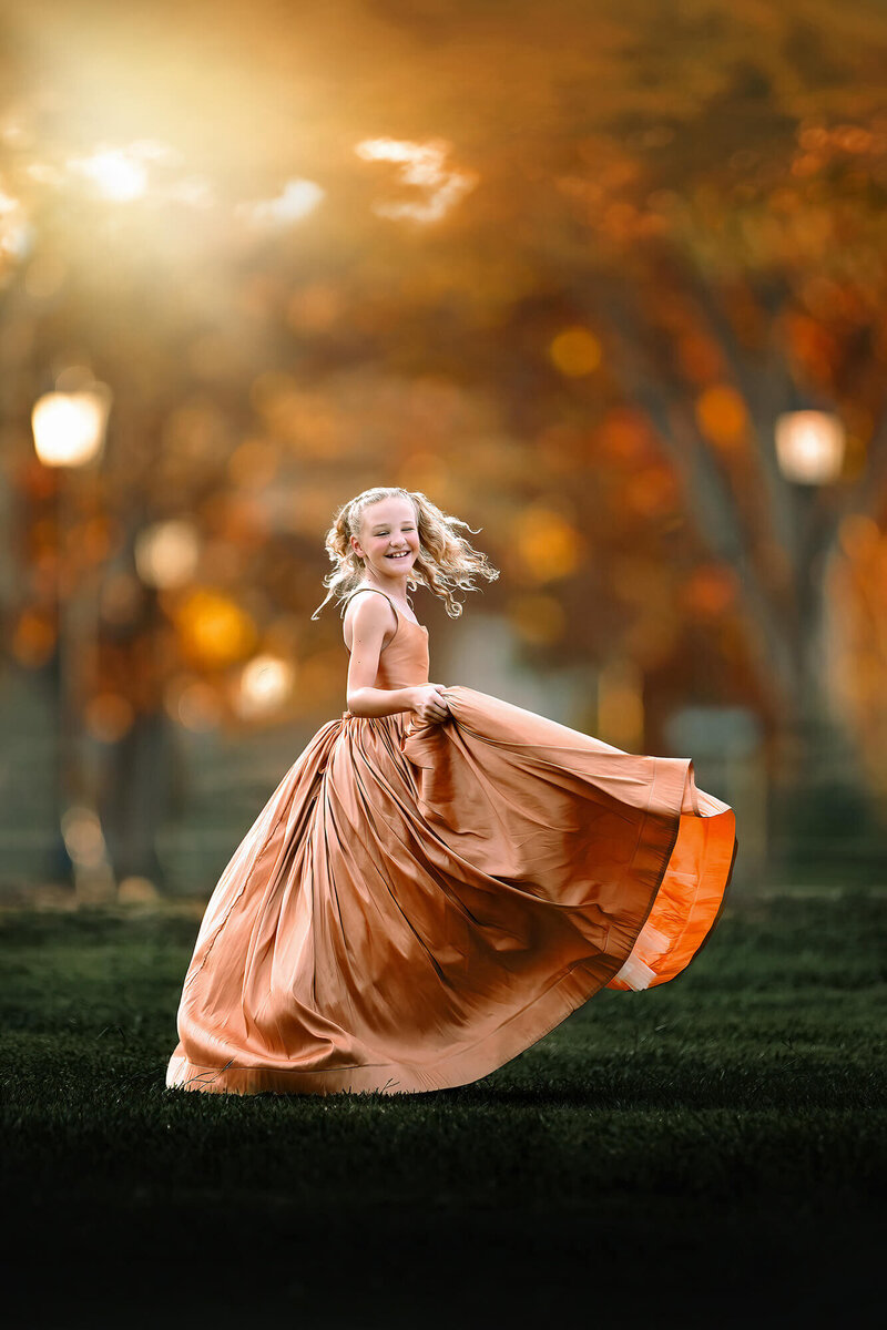 Beautiful little girl twirling in a golden dress