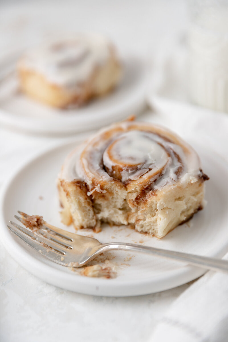 a cinnamon roll on a plate with a bite taken out of it