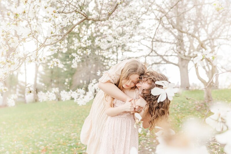 mom kisses daughter during spring photo session  in Wellesley Massachusetts with  Sara Sniderman Photography