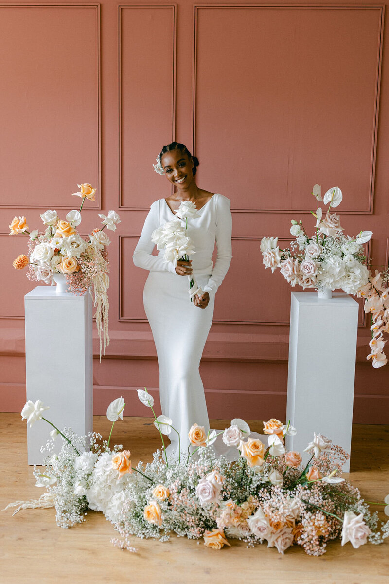 bride holding white roses surrounded by luxury floral display