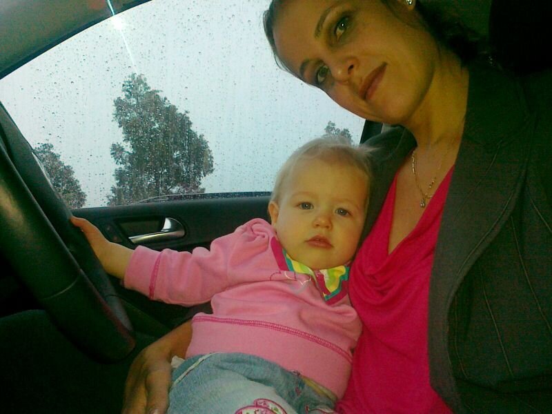Salome  sitting in her car cradling her 10 month old daughter Milla