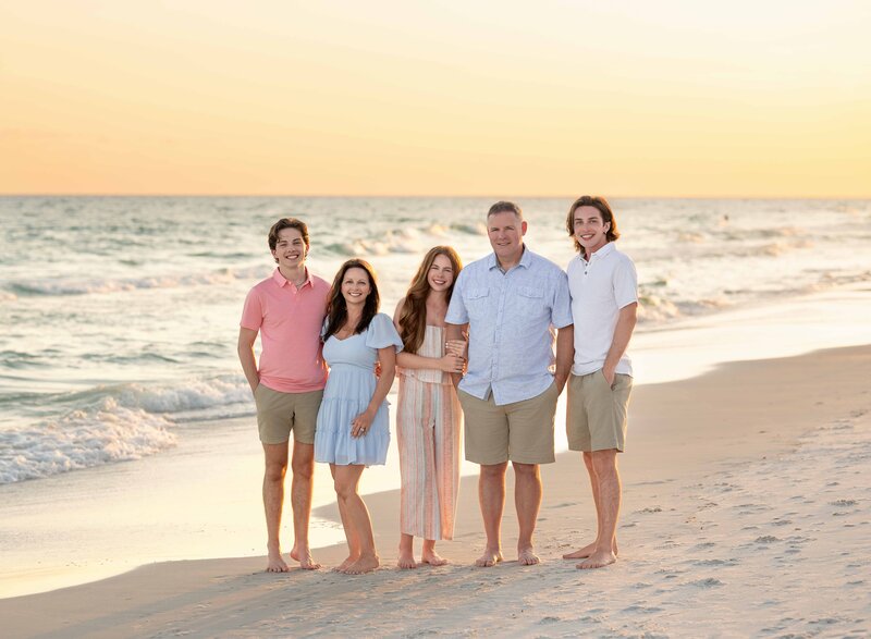 Family of 5 dressed in pinks and blues, taking professional photo on Seaside Beach, FL.