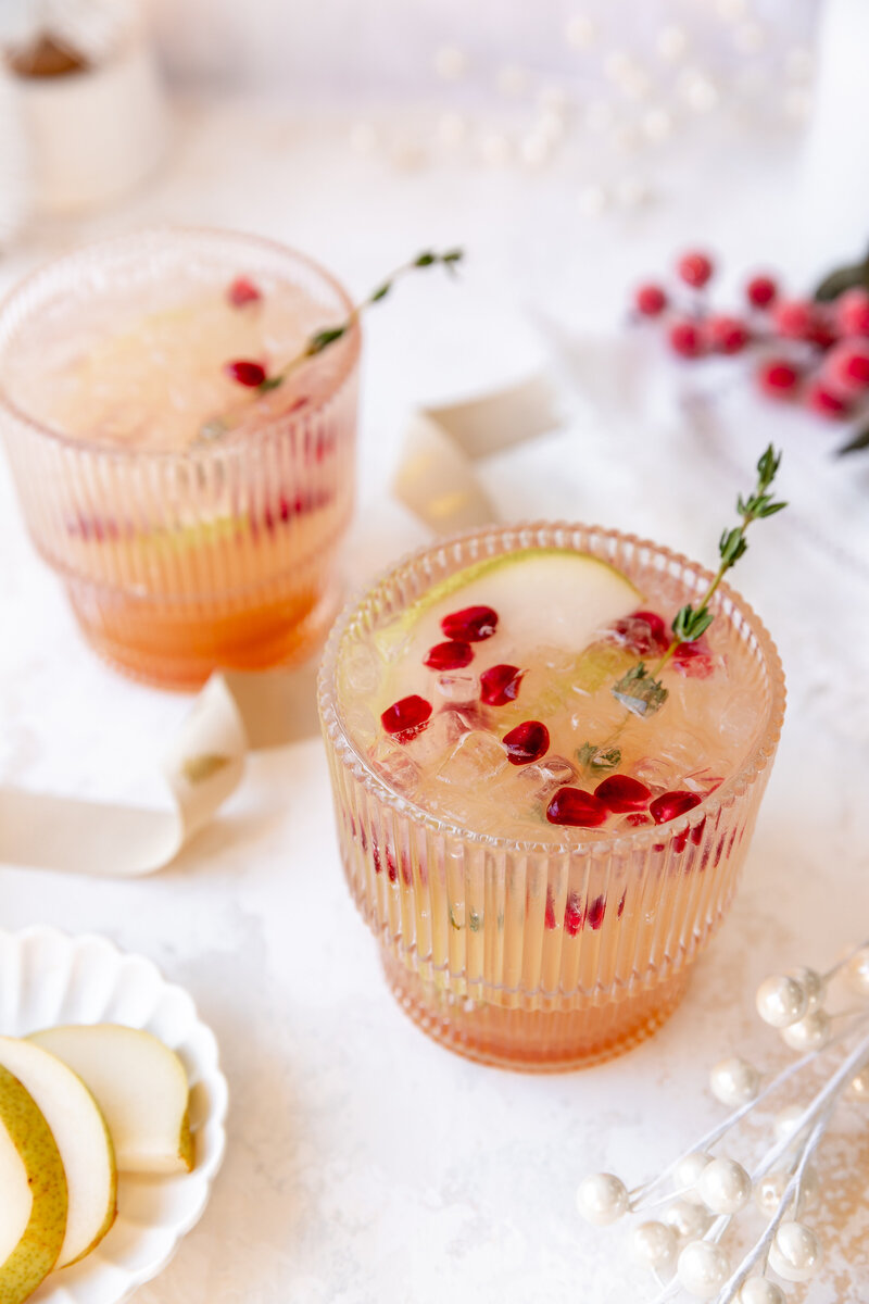 a cocktail in a glass garnished with cranberries