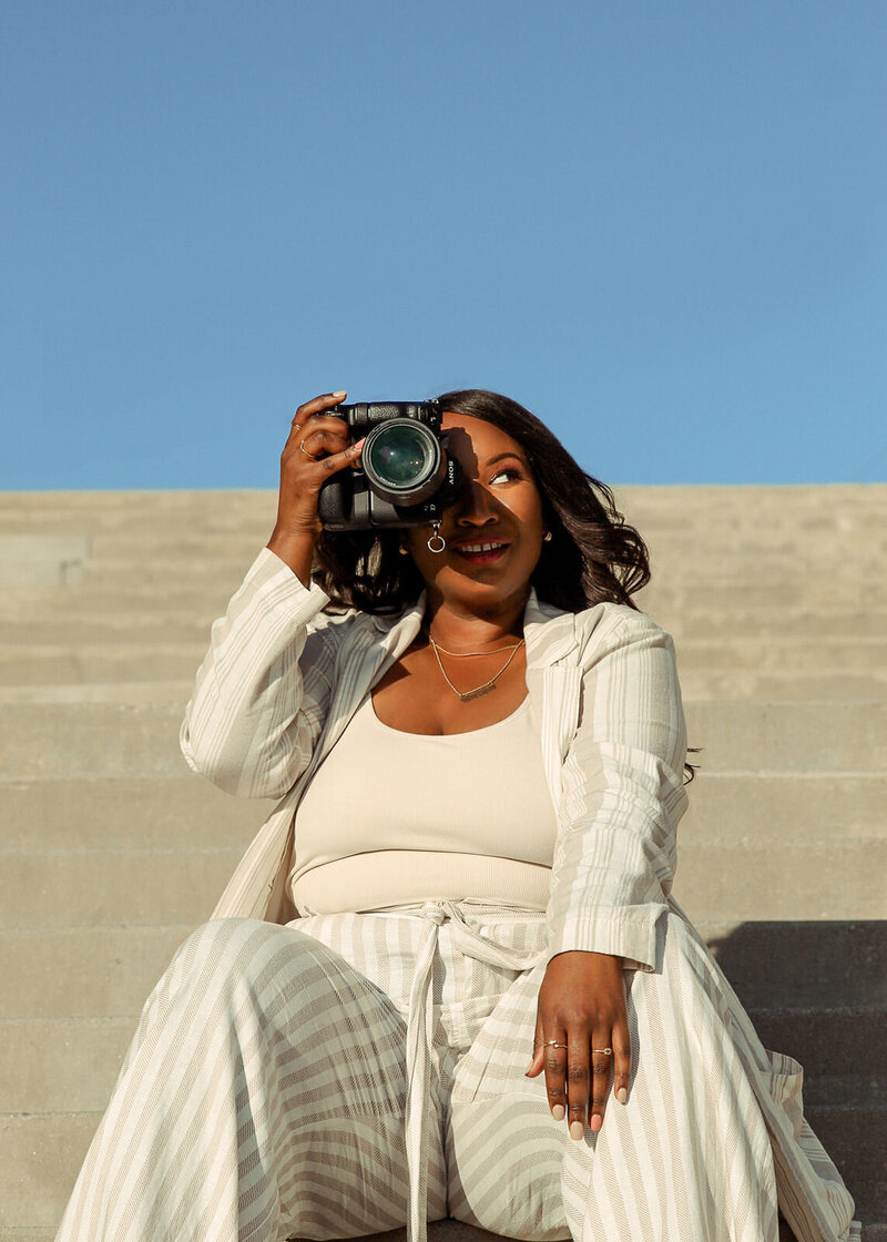 Black female photographer holding camera  and taking pictures