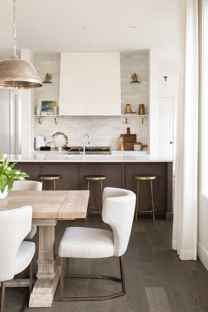 Dining space and kitchen area with light upholstery and brass details. 