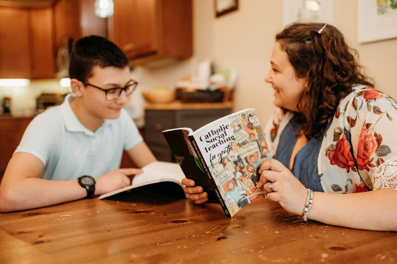 mother and son sitting at kitchen table reading a book