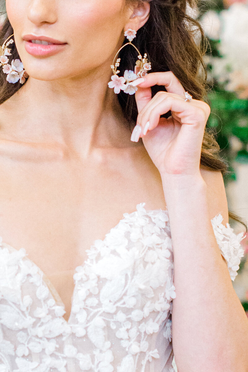 Close up image of a bride touching her floral earrings