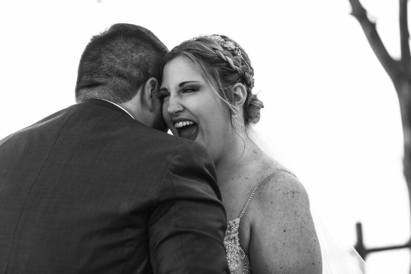 Bride laughing as groom whispers something in her ear at Beach Glass Estates wedding