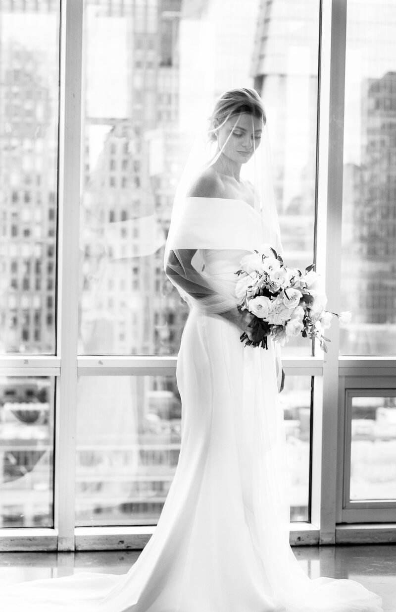 Black and white portrait of bride in an elegant dress with veil overlooking the city at the Chelsea Blass House venue.