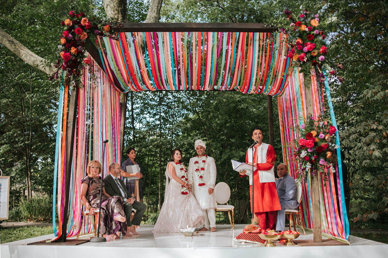 Bride and groom celebrating beneath a ribbon canopy at their wedding ceremony at Bartram’s Garden in Philadelphia